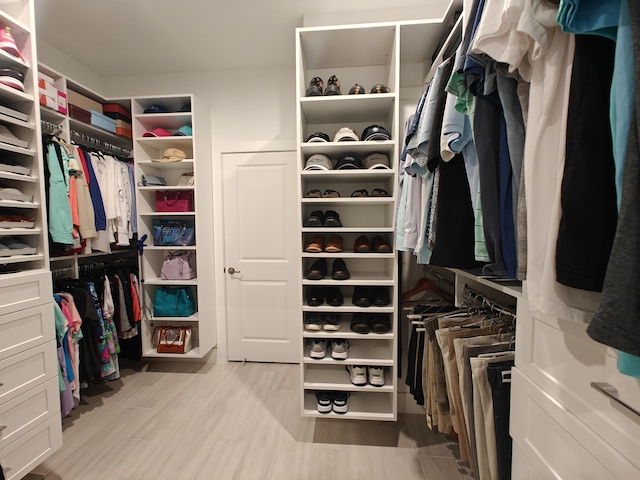 walk in closet with light hardwood / wood-style floors