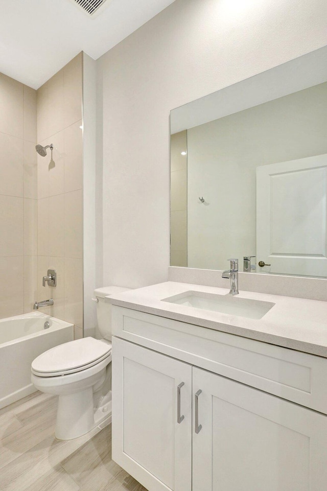 full bathroom featuring vanity, tiled shower / bath combo, and toilet