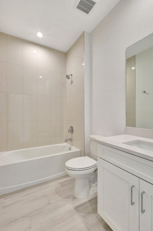 full bathroom featuring tiled shower / bath combo, toilet, and vanity