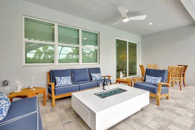 view of patio featuring ceiling fan and an outdoor living space with a fire pit