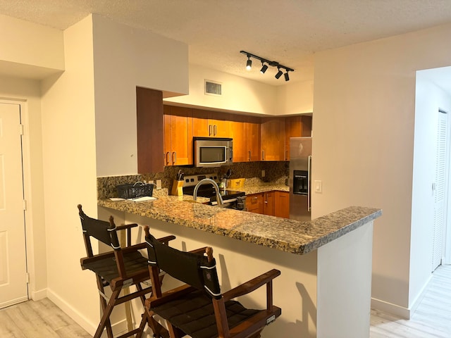 kitchen featuring appliances with stainless steel finishes, a kitchen breakfast bar, light hardwood / wood-style floors, and kitchen peninsula