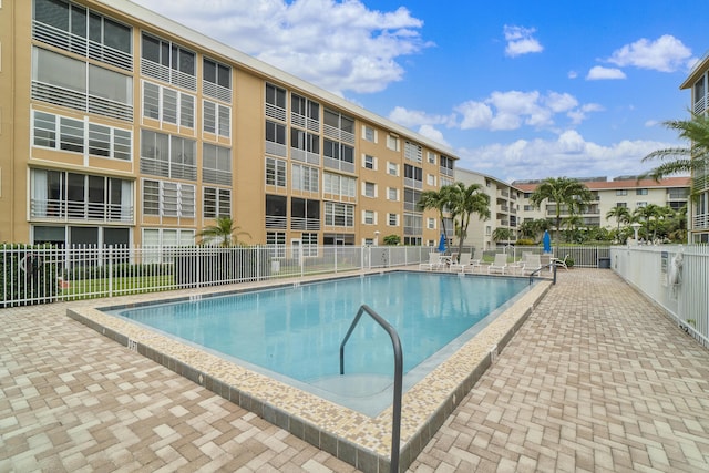 community pool with a patio area and fence