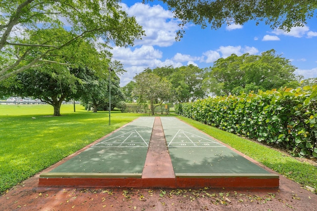 view of community with shuffleboard and a yard