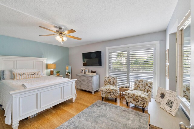 bedroom featuring light wood-type flooring, ceiling fan, and a textured ceiling