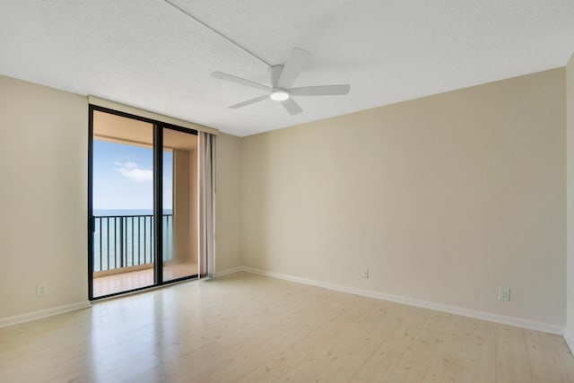 empty room with floor to ceiling windows, a textured ceiling, and light wood-type flooring