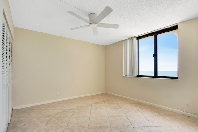 tiled empty room featuring ceiling fan and a textured ceiling