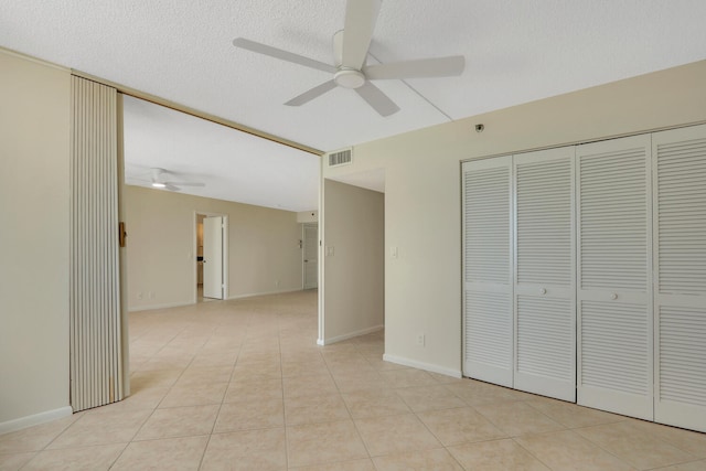 unfurnished bedroom featuring light tile patterned flooring, a textured ceiling, ceiling fan, and a closet