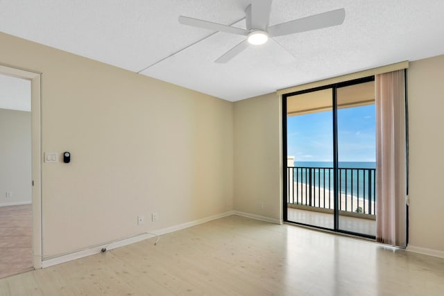 unfurnished room with light hardwood / wood-style flooring, floor to ceiling windows, a healthy amount of sunlight, and a water view