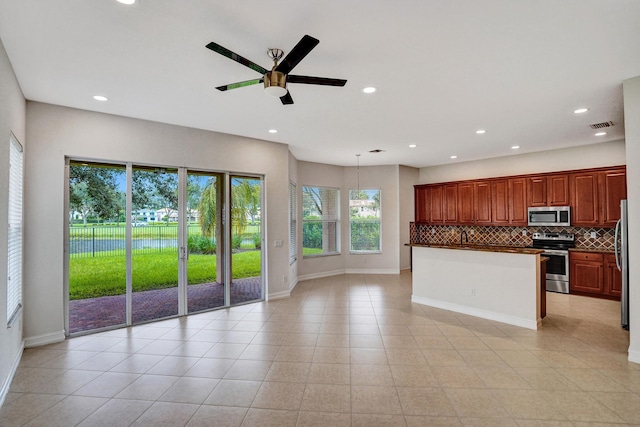 kitchen with appliances with stainless steel finishes, ceiling fan, hanging light fixtures, and decorative backsplash