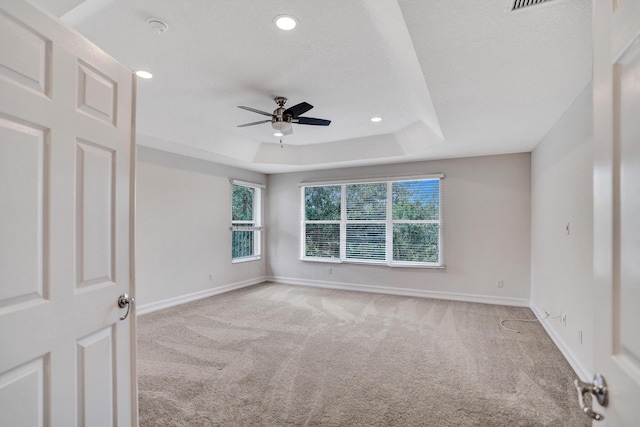 carpeted spare room featuring ceiling fan and a tray ceiling