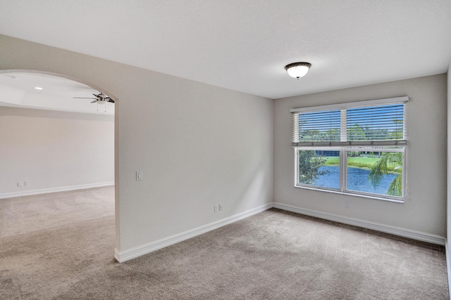 carpeted spare room featuring ceiling fan and a water view