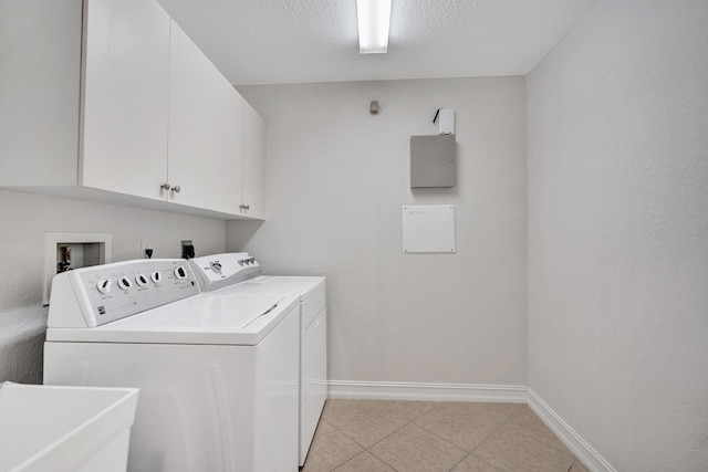 laundry room with cabinets, light tile patterned floors, a textured ceiling, sink, and washer and clothes dryer