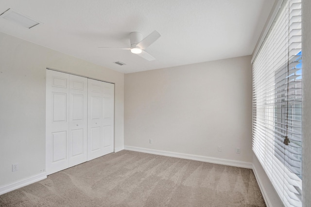 unfurnished bedroom featuring light colored carpet, ceiling fan, and a closet