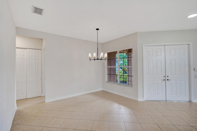 unfurnished room with an inviting chandelier and light tile patterned floors