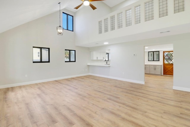 unfurnished living room with ceiling fan, high vaulted ceiling, and light hardwood / wood-style floors