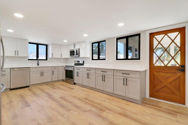 kitchen with a wealth of natural light, appliances with stainless steel finishes, and light hardwood / wood-style floors