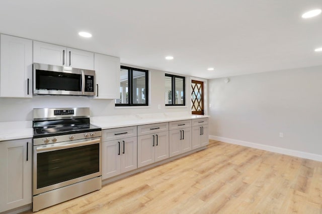 kitchen with light wood-type flooring, white cabinetry, stainless steel appliances, and light stone countertops