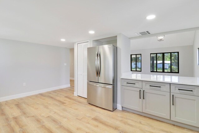 kitchen featuring light stone counters, stainless steel refrigerator, and light hardwood / wood-style floors