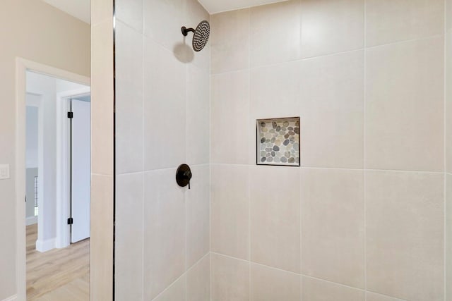 bathroom with hardwood / wood-style flooring and a tile shower