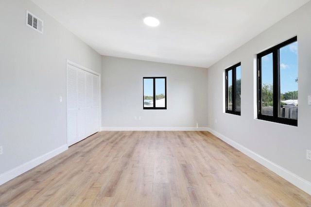 empty room featuring vaulted ceiling and light hardwood / wood-style flooring