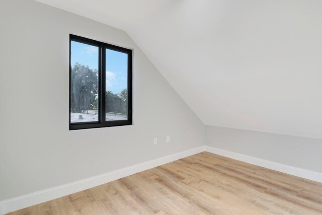 additional living space featuring light wood-type flooring and lofted ceiling