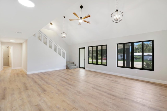 unfurnished living room with high vaulted ceiling, ceiling fan with notable chandelier, and light hardwood / wood-style floors