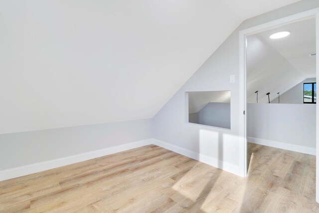 additional living space featuring lofted ceiling and light hardwood / wood-style flooring