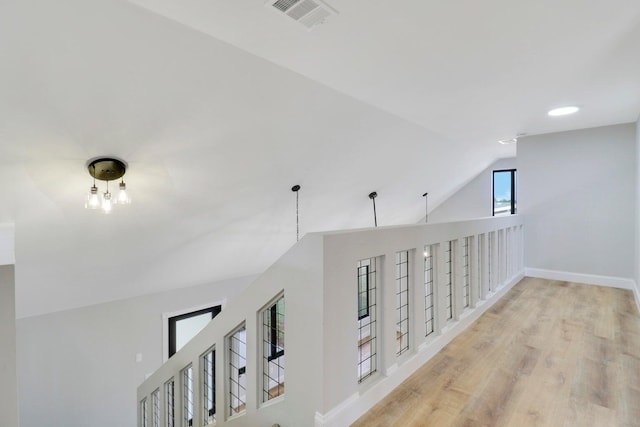 corridor with light hardwood / wood-style flooring and vaulted ceiling