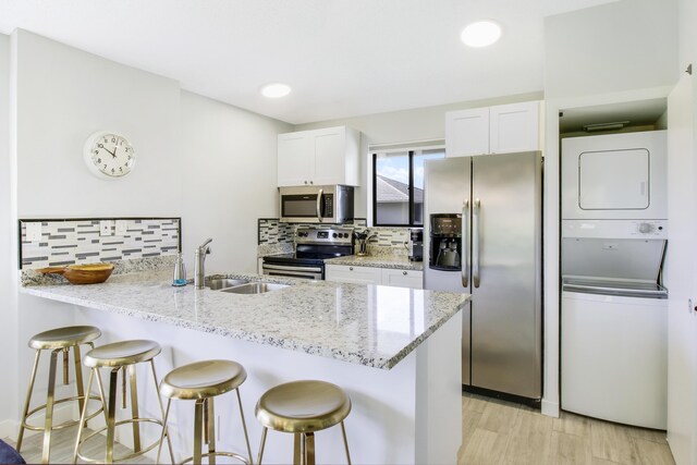 kitchen with stainless steel appliances, sink, kitchen peninsula, and white cabinets