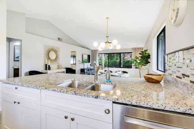 kitchen with sink, light stone countertops, lofted ceiling, stainless steel dishwasher, and white cabinets