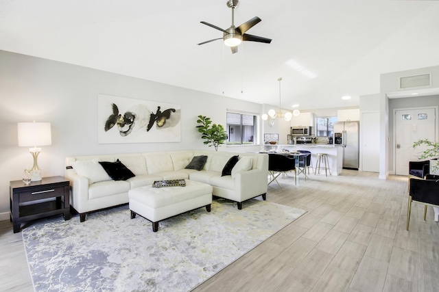 living room with light wood finished floors, visible vents, ceiling fan with notable chandelier, and lofted ceiling