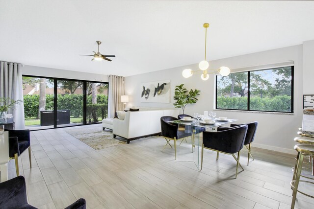 dining space with ceiling fan with notable chandelier and light hardwood / wood-style floors