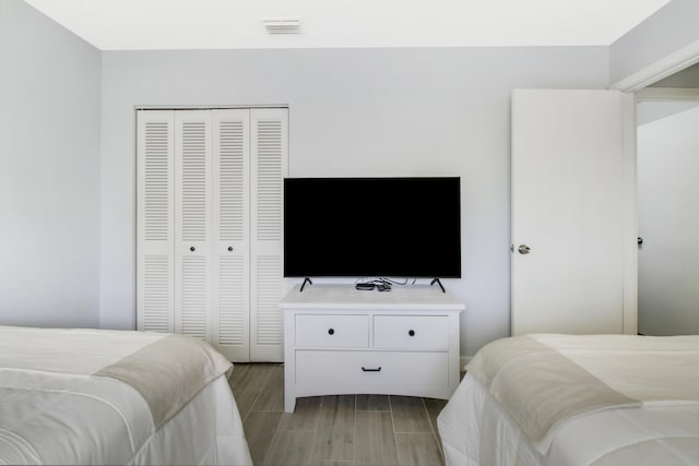 bedroom with visible vents, a closet, and wood finish floors