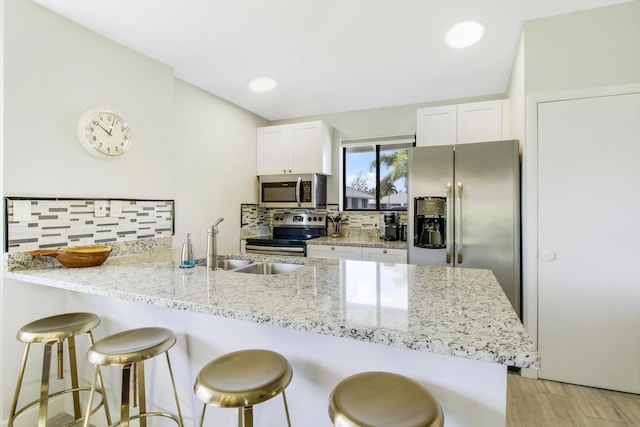 kitchen with a peninsula, a breakfast bar area, tasteful backsplash, and appliances with stainless steel finishes