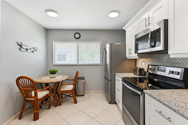 kitchen featuring white cabinets, light stone countertops, light tile patterned floors, tasteful backsplash, and stainless steel appliances