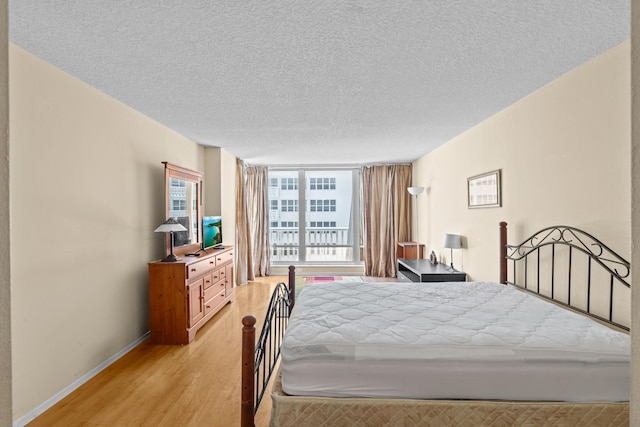 bedroom with a textured ceiling, light hardwood / wood-style flooring, and floor to ceiling windows