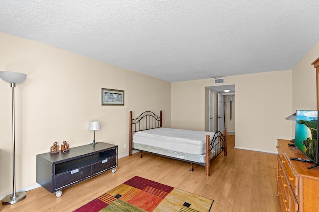 bedroom featuring a textured ceiling and light hardwood / wood-style flooring