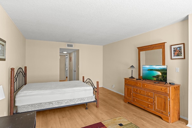 bedroom with a textured ceiling and light hardwood / wood-style flooring