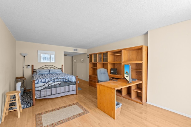 bedroom with light wood-type flooring and a textured ceiling