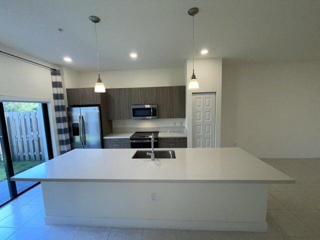 kitchen featuring dark brown cabinets, stainless steel appliances, a kitchen island with sink, and sink