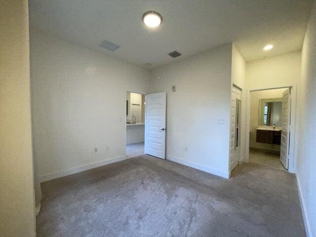 unfurnished bedroom with carpet floors and ensuite bath