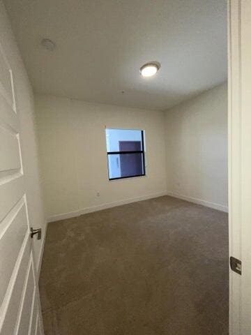 unfurnished room with dark colored carpet