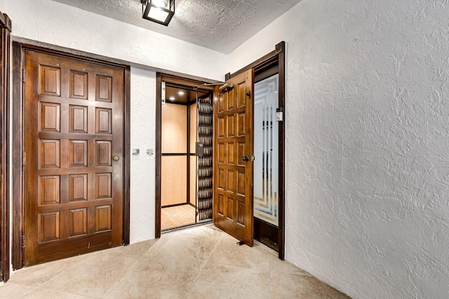 entryway with light tile patterned floors and a textured ceiling