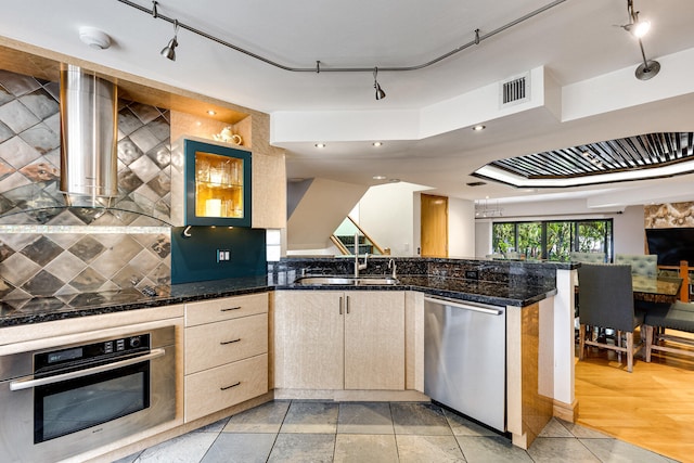 kitchen featuring dark stone countertops, tasteful backsplash, stainless steel appliances, sink, and light hardwood / wood-style floors