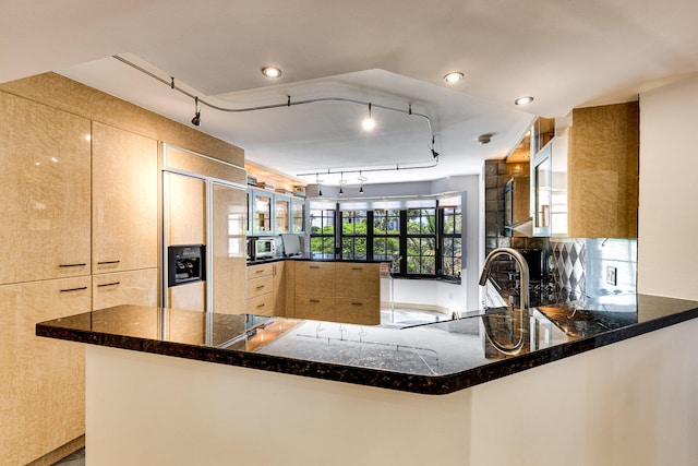 kitchen with light brown cabinetry, paneled built in fridge, sink, kitchen peninsula, and track lighting