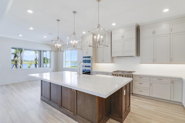 kitchen featuring a large island, white cabinets, pendant lighting, and wall chimney exhaust hood