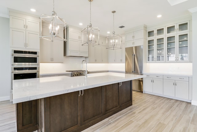 kitchen featuring decorative light fixtures, stainless steel appliances, a spacious island, and light wood-type flooring