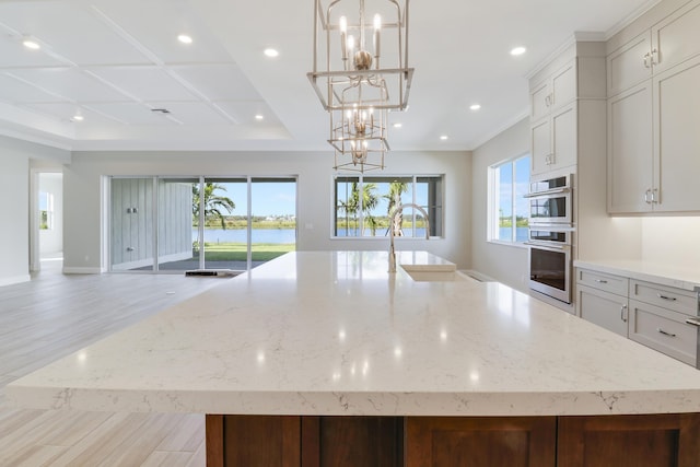 kitchen with light stone countertops, a large island, a chandelier, and decorative light fixtures