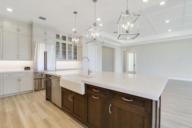 kitchen with a spacious island, sink, light wood-type flooring, appliances with stainless steel finishes, and pendant lighting