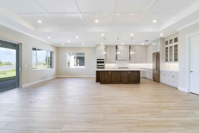 kitchen with sink, a center island with sink, pendant lighting, stainless steel appliances, and white cabinets